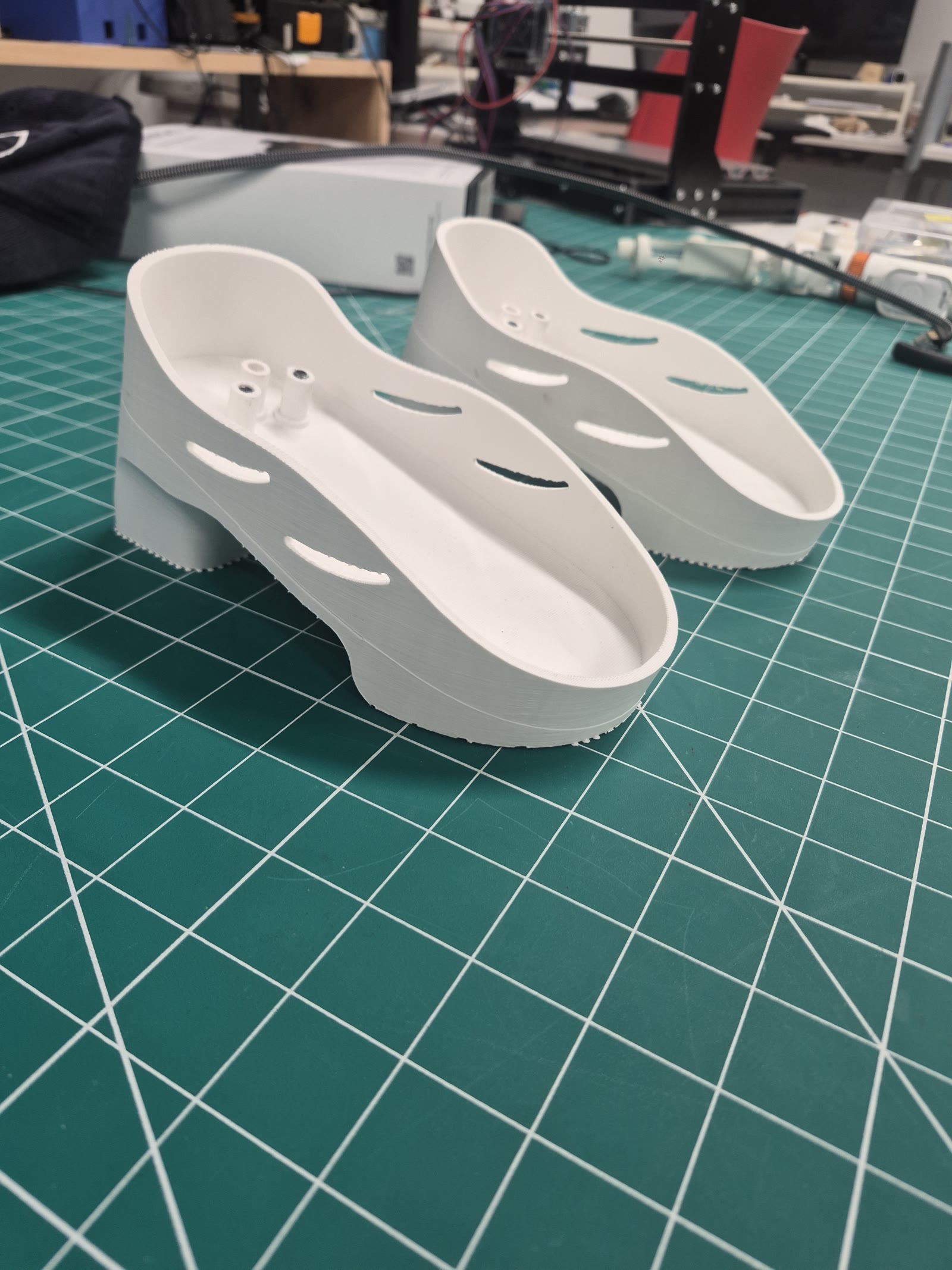 A pair of white 3D-printed heel shoes on a cutting mat